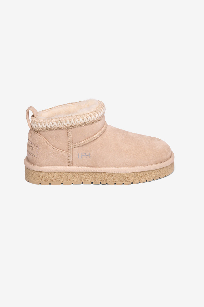 Boots fourrées beige rosé à bordure tricotée écrue et beige, semelle épaisse gomme, vue de profil.