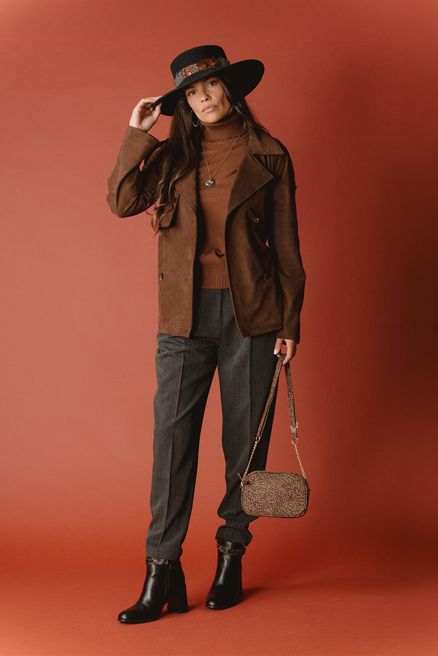Pull Pasquine choco à col roulé, porté sous une veste en suédine marron avec un pantalon gris et un sac imprimé léopard.
