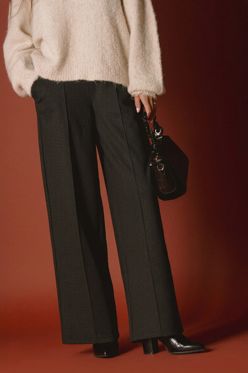 Pantalon Philippa imprimé Dundee noir large, porté avec un pull beige en maille et un sac à main noir.