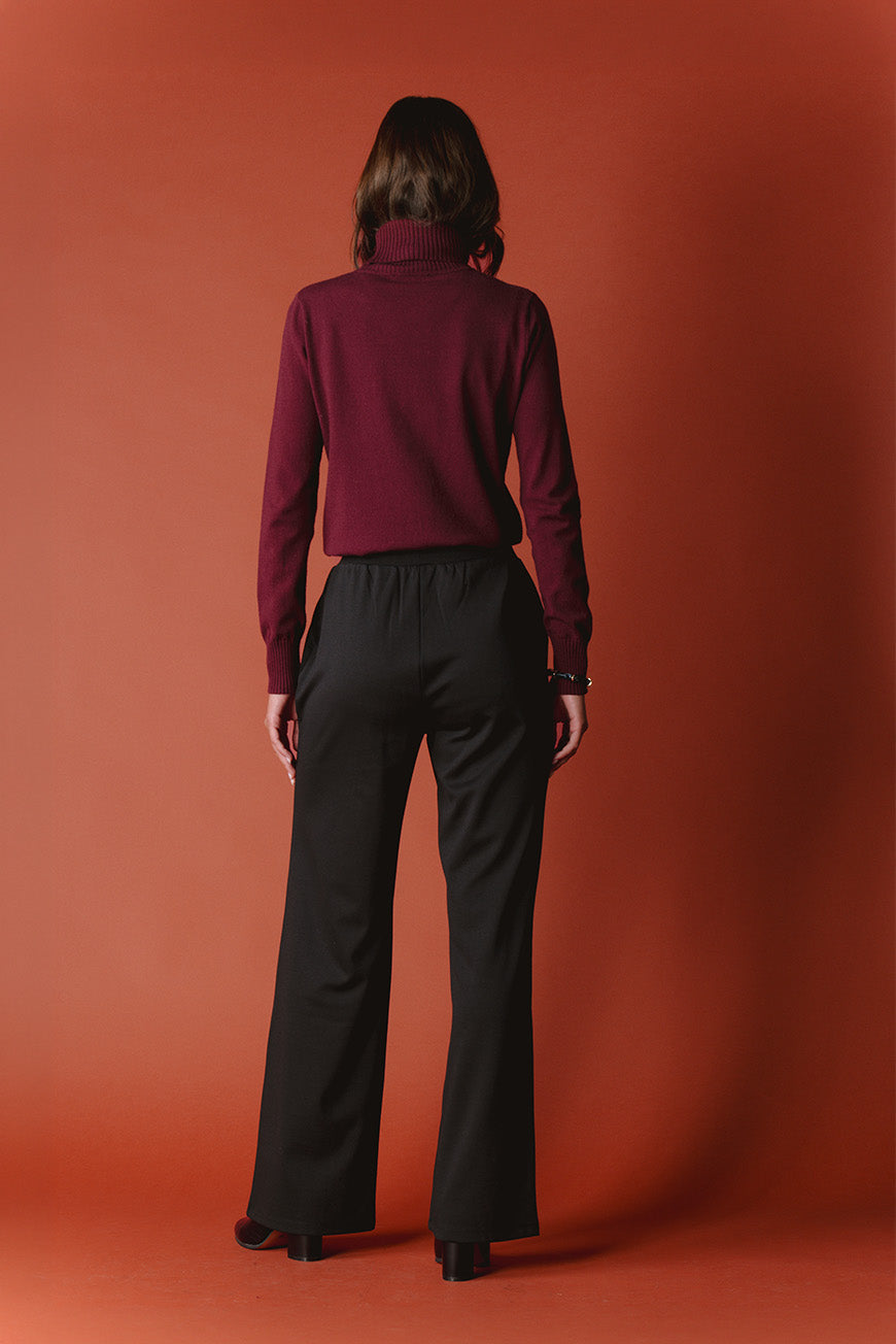 Pantalon Pharailde noir large vue de dos, porté avec un pull bordeaux à col roulé.