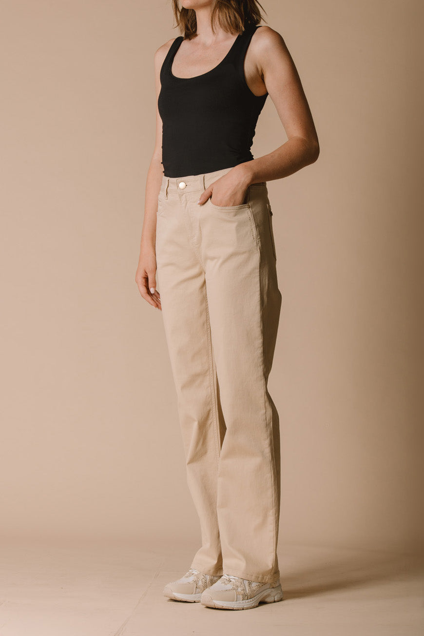 Pantalon Paola beige droit vue de profil, porté avec un débardeur noir et des baskets blanches.