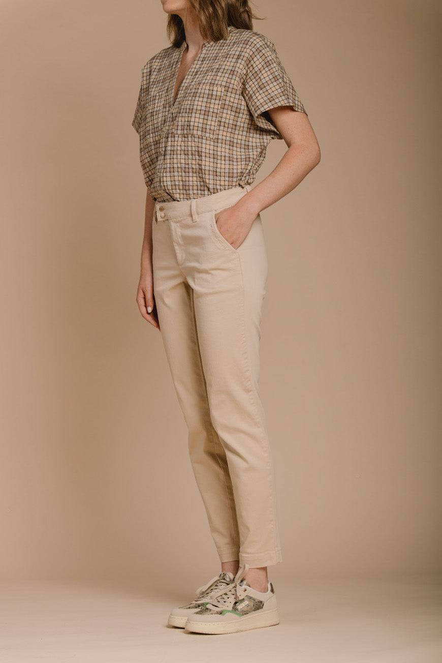 Pantalon Naomie beige slim vue de profil, porté avec une chemise à carreaux et des baskets.