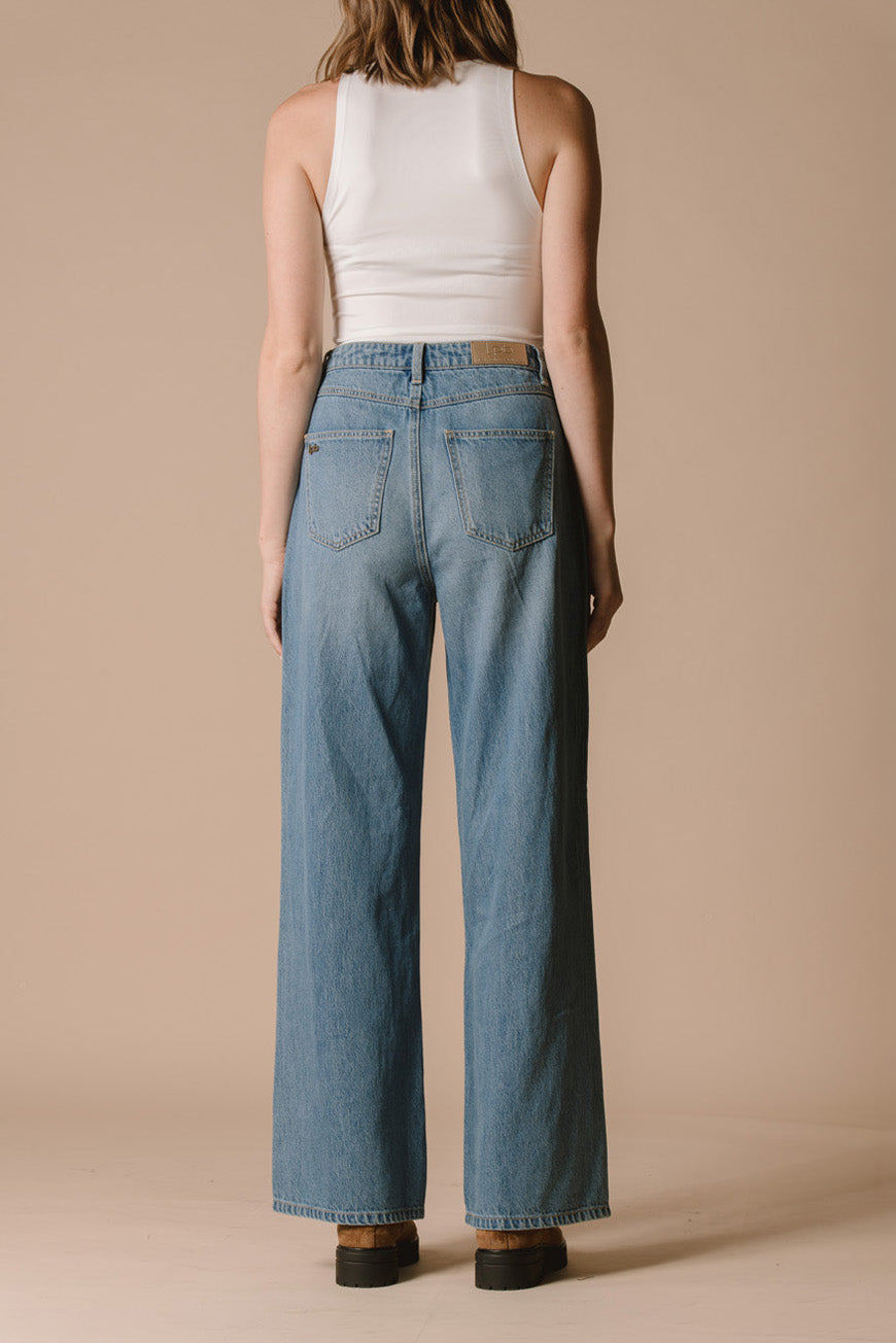 Pantalon Prew bleu large vue de dos, porté avec des bottines camel.