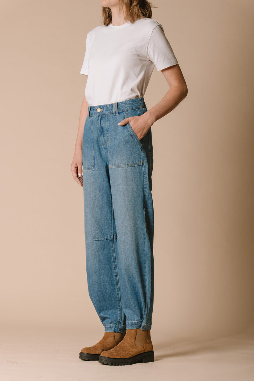 Pantalon Polonie bleu vue de profil, porté avec des bottines camel.