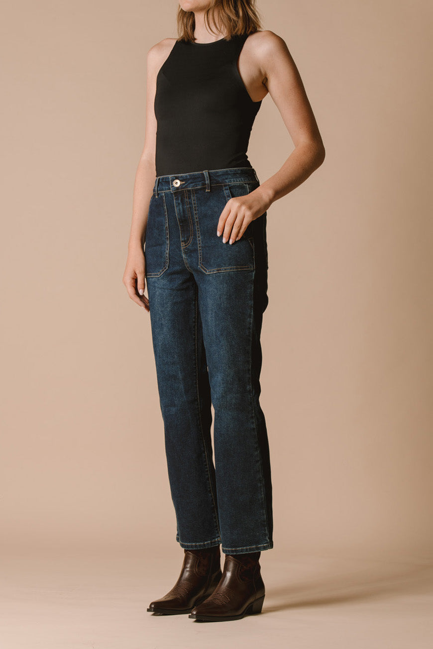 Jean bootcut Indiana crop vue de profil, porté avec un débardeur noir et des santiags marron.