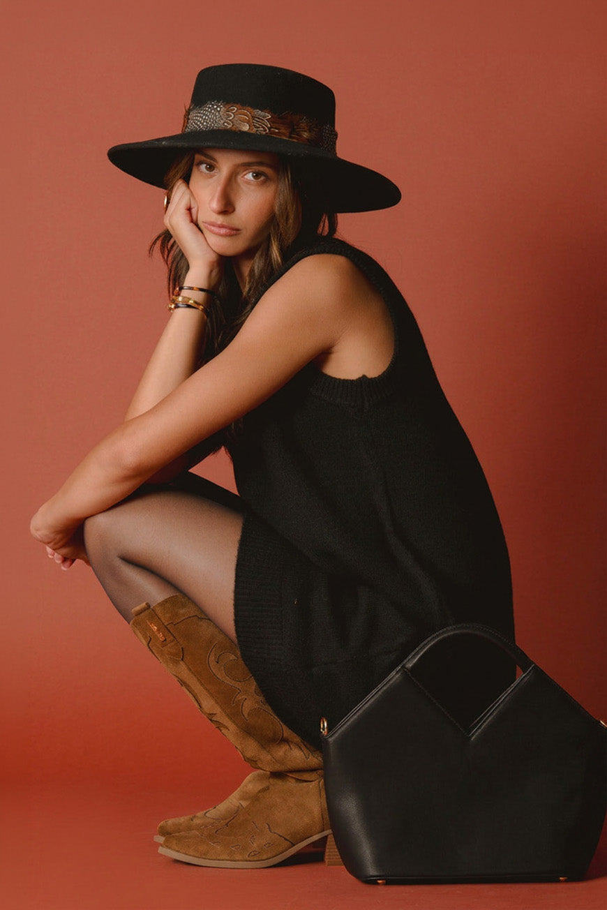 Robe Pearl noire portée accroupie avec des santiags camel et un sac noir