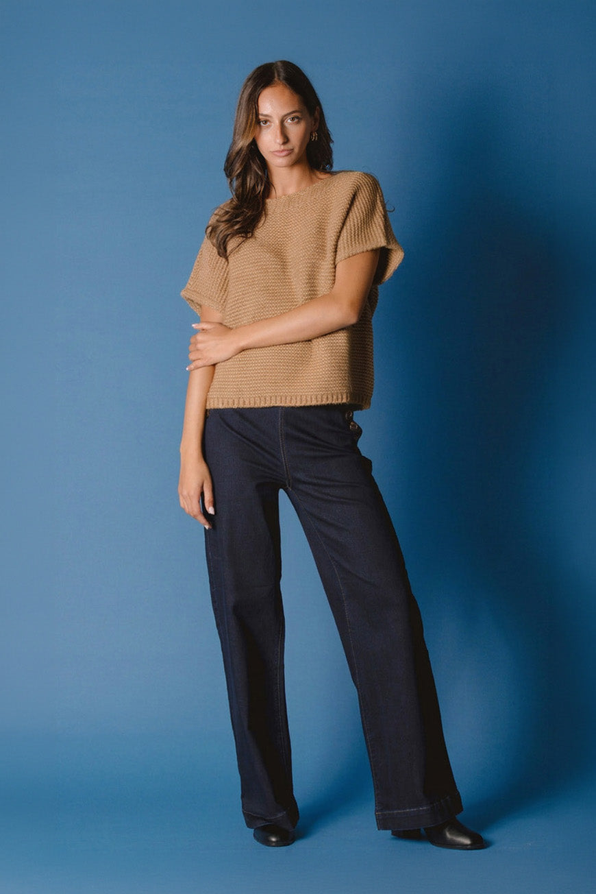 Pull Naciye camel sans manches, porté bras croisés avec un jean brut